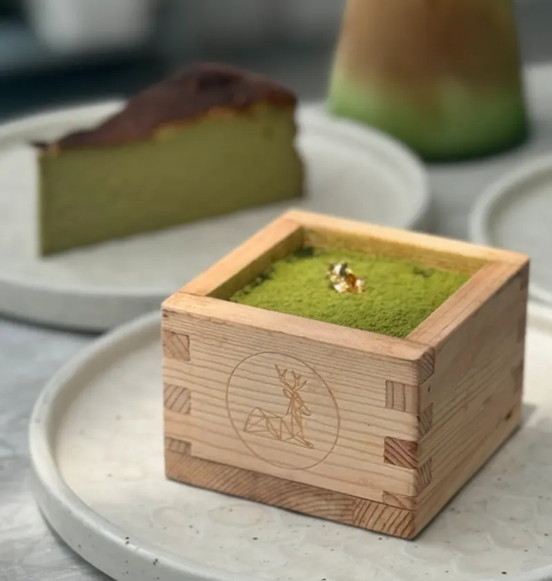 Matcha tiramisu in a wooden masu box with gold leaf